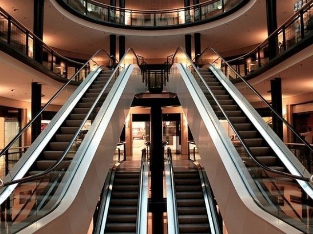 Vista simétrica de dos escaleras mecánicas que se cruzan y que conducen a las plantas superiores de un moderno centro comercial de varias plantas.