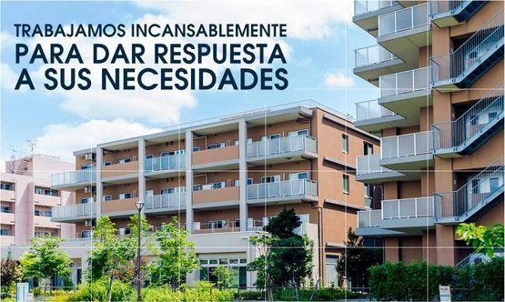 Edificios de apartamentos modernos rodeados de vegetación bajo un cielo azul, con el texto en español: "Trabajamos incansablemente para satisfacer sus necesidades".