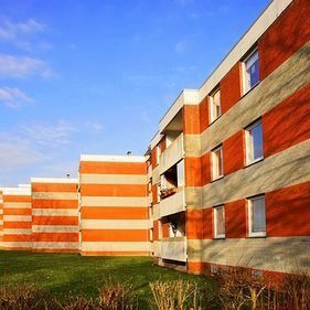 Edificios de apartamentos residenciales con distintivas franjas horizontales de color naranja y gris claro sobre un cielo azul despejado.