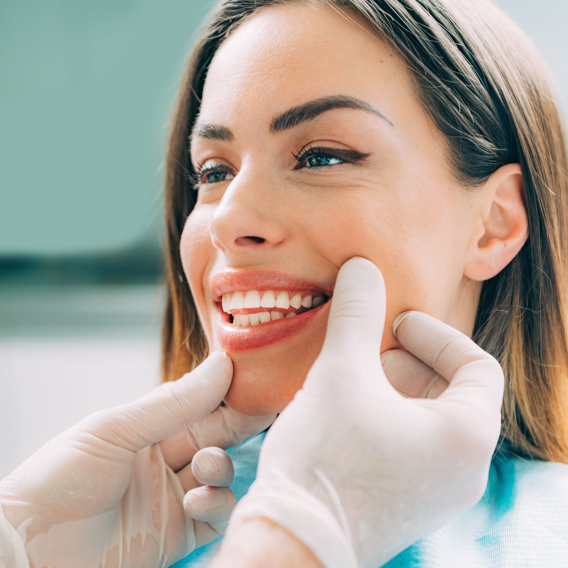Una mujer sonríe mientras un dentista le examina los dientes.