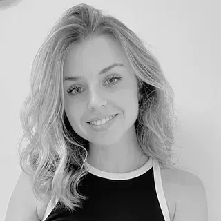 Una fotografía en blanco y negro de una mujer que viste una camiseta negra sin mangas y sonríe.