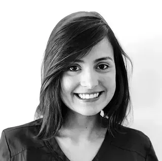 Una fotografía en blanco y negro de una mujer sonriente que viste una blusa quirúrgica.