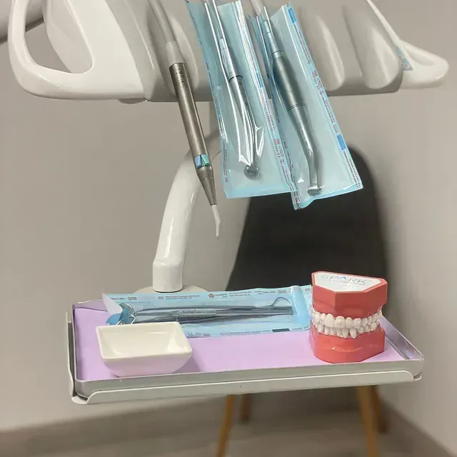 Una bandeja con instrumentos dentales y un modelo de dientes sobre ella.