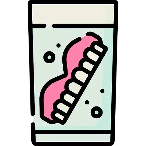 Una dentadura postiza está colocada en un vaso de agua.