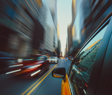 Voiture jaune roulant rapidement dans une rue de la ville avec des lignes de mouvement floues.