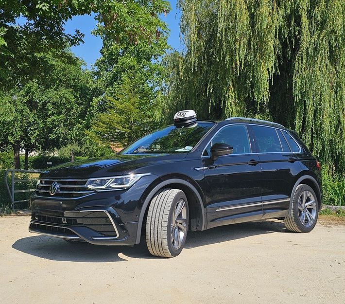 SUV Volkswagen noir avec capteur sur le toit garé sur un chemin de terre près des arbres.