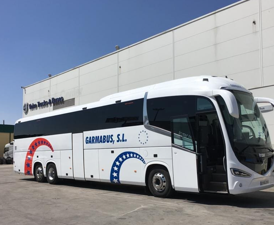Un gran autobús blanco está estacionado frente a un edificio.