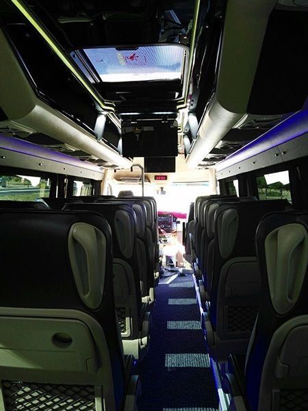 El interior de un autobús con muchos asientos y una alfombra azul.