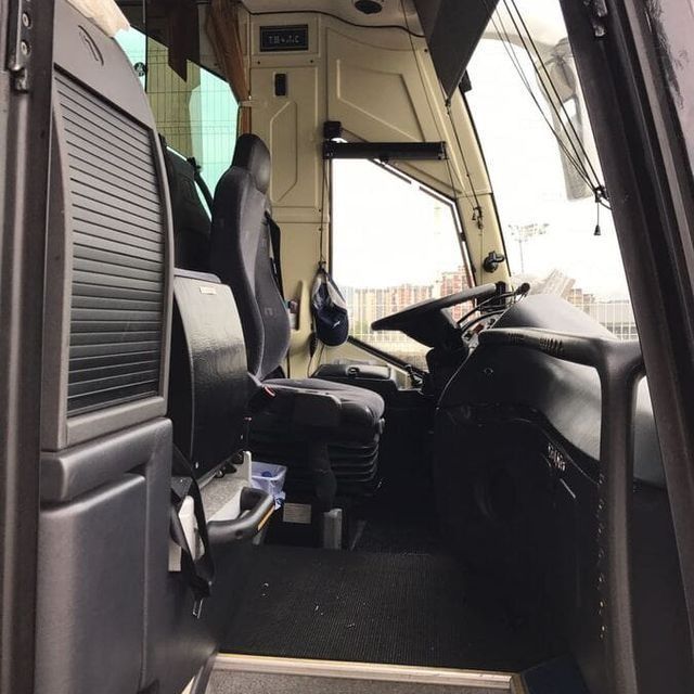 El interior de un autobús con volante y asientos.