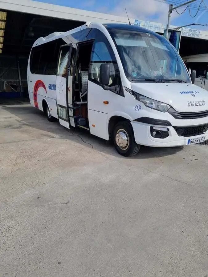 Un autobús blanco está estacionado en un estacionamiento frente a un edificio.