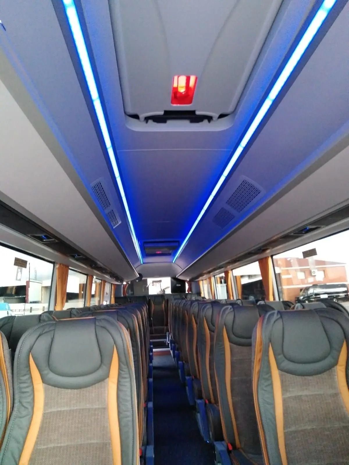 El interior de un autobús con luces azules en el techo.