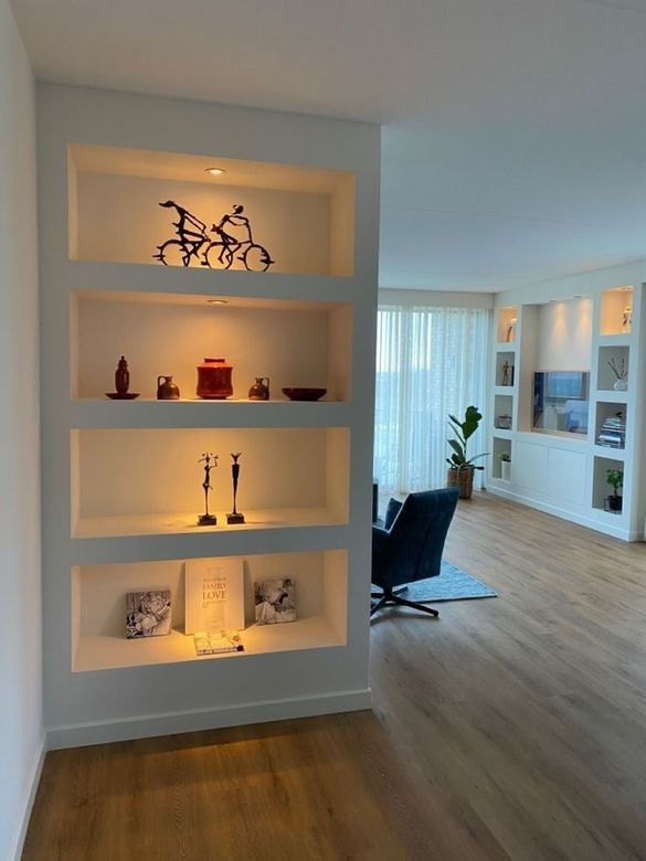 Una estantería empotrada blanca con cuatro nichos iluminados para colocar objetos decorativos en un salón luminoso y moderno.