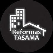 Logotipo para "Reformas TASAMA" que presenta un edificio y el contorno de una casa, en blanco sobre un círculo negro.