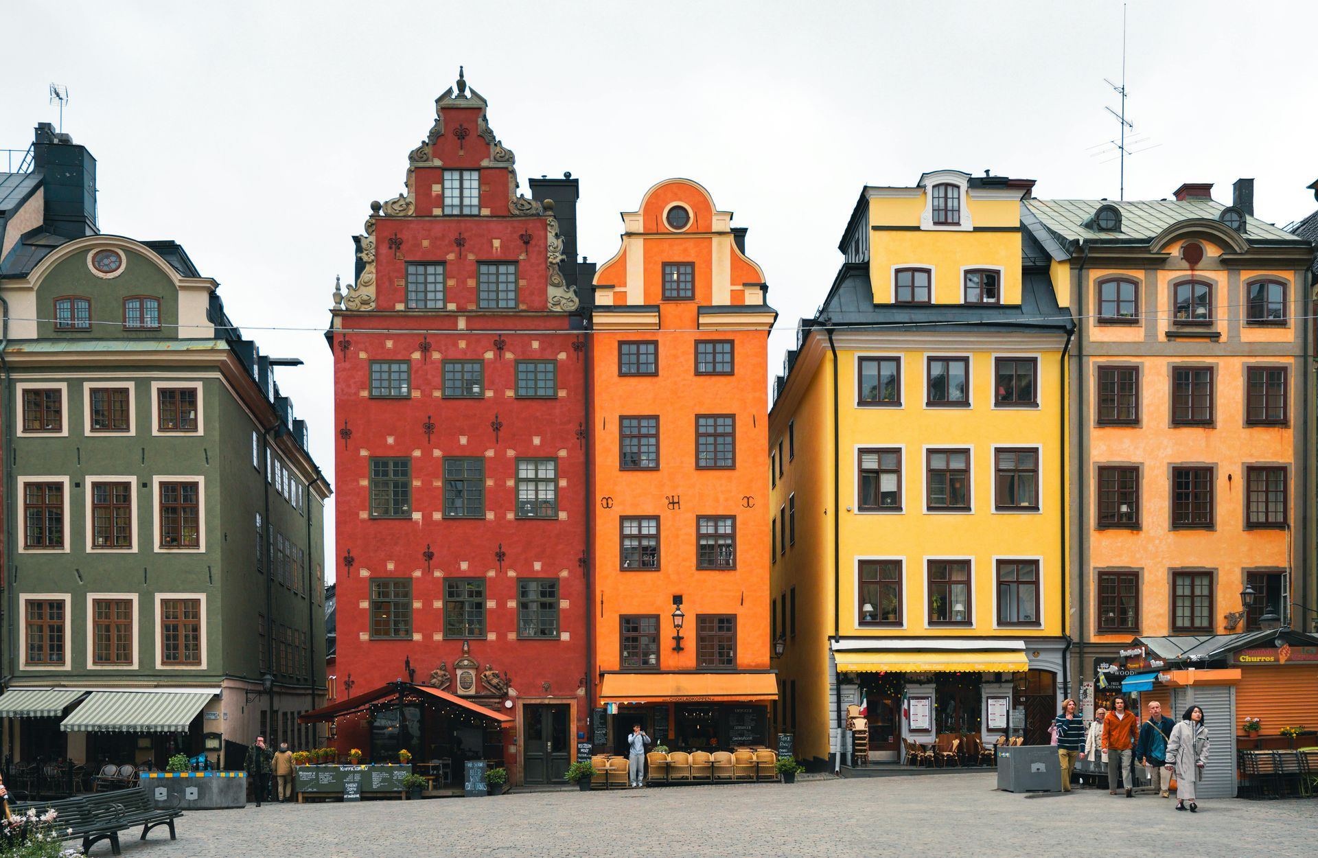 Casas adosadas históricas y coloridas a lo largo de una plaza adoquinada en una plaza de un pueblo europeo.