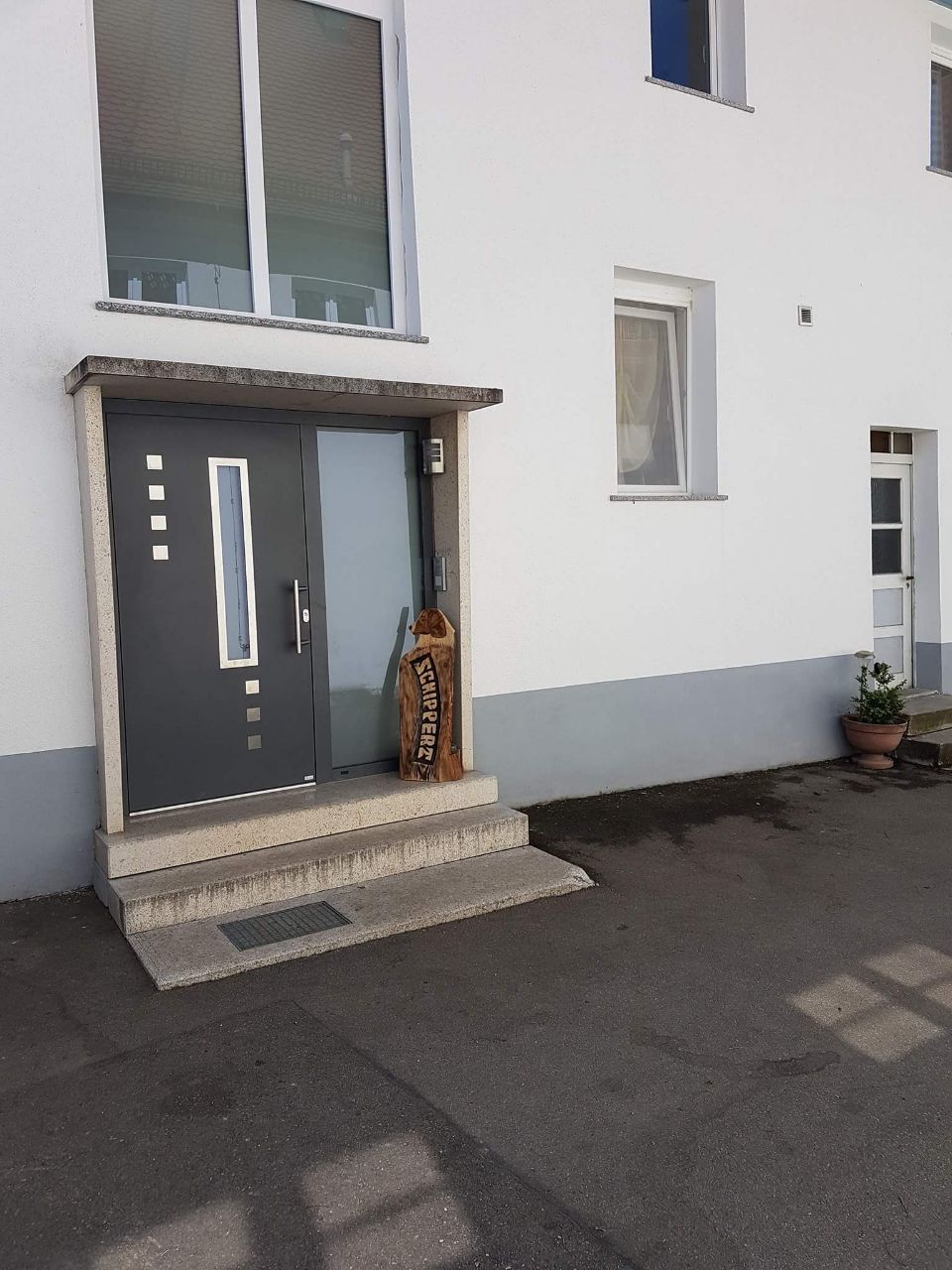 Ein weißes Gebäude mit einer schwarzen Tür und schwarzen Fenstern