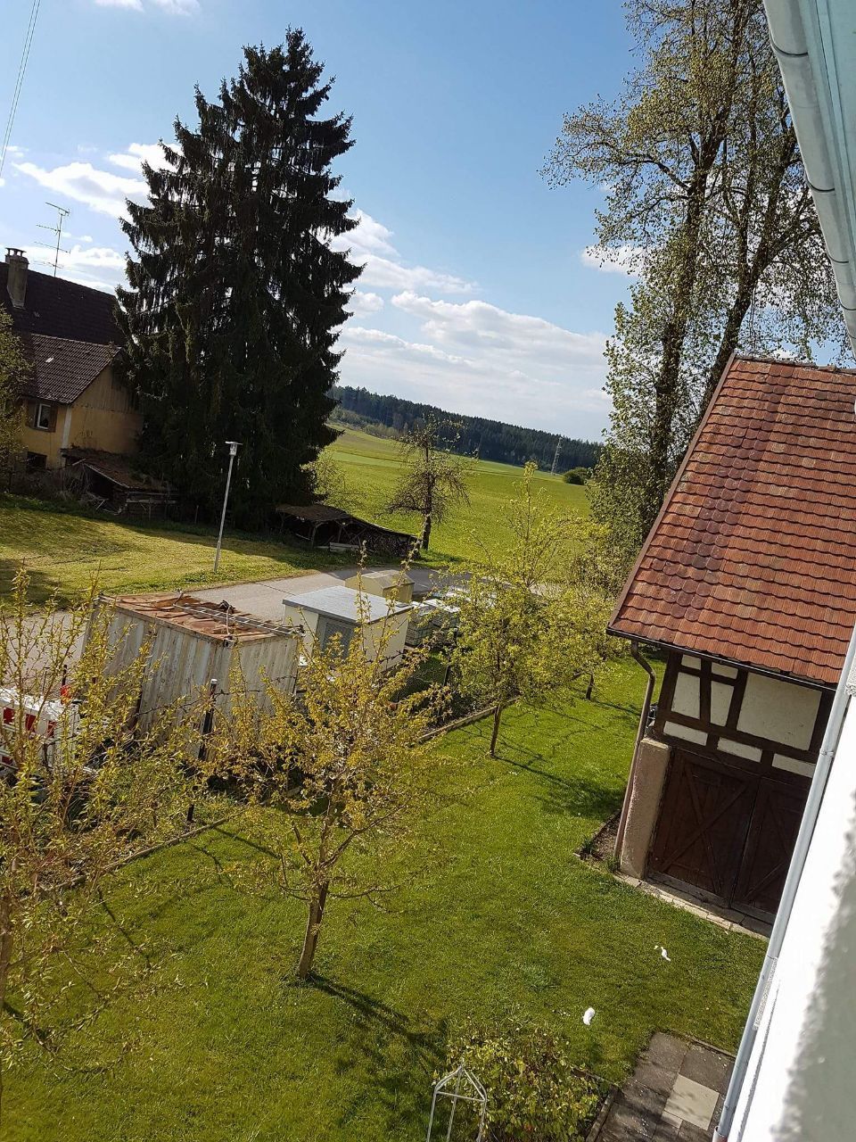 Ein Haus mit einem roten Ziegeldach ist von Bäumen und Gras umgeben.