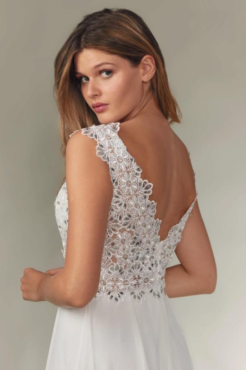 Mujer con vestido blanco con corpiño adornado, mirando por encima del hombro.