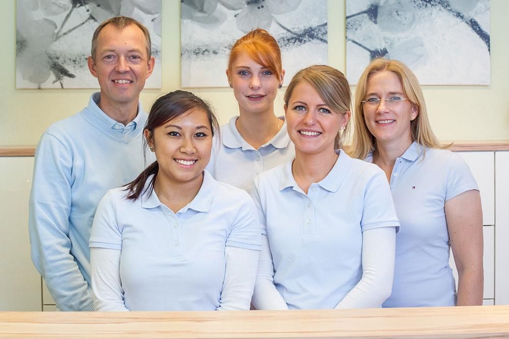 Eine Gruppe von Menschen posiert vor einem Tresen für ein Foto.