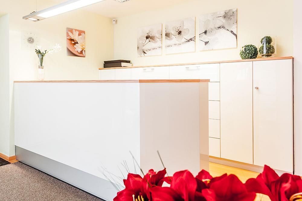 Eine weiße Theke in einem Raum mit roten Blumen davor.