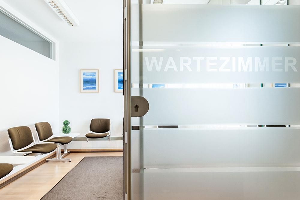 Ein Wartezimmer mit einer Glastür, auf der steht „Wartezimmer“