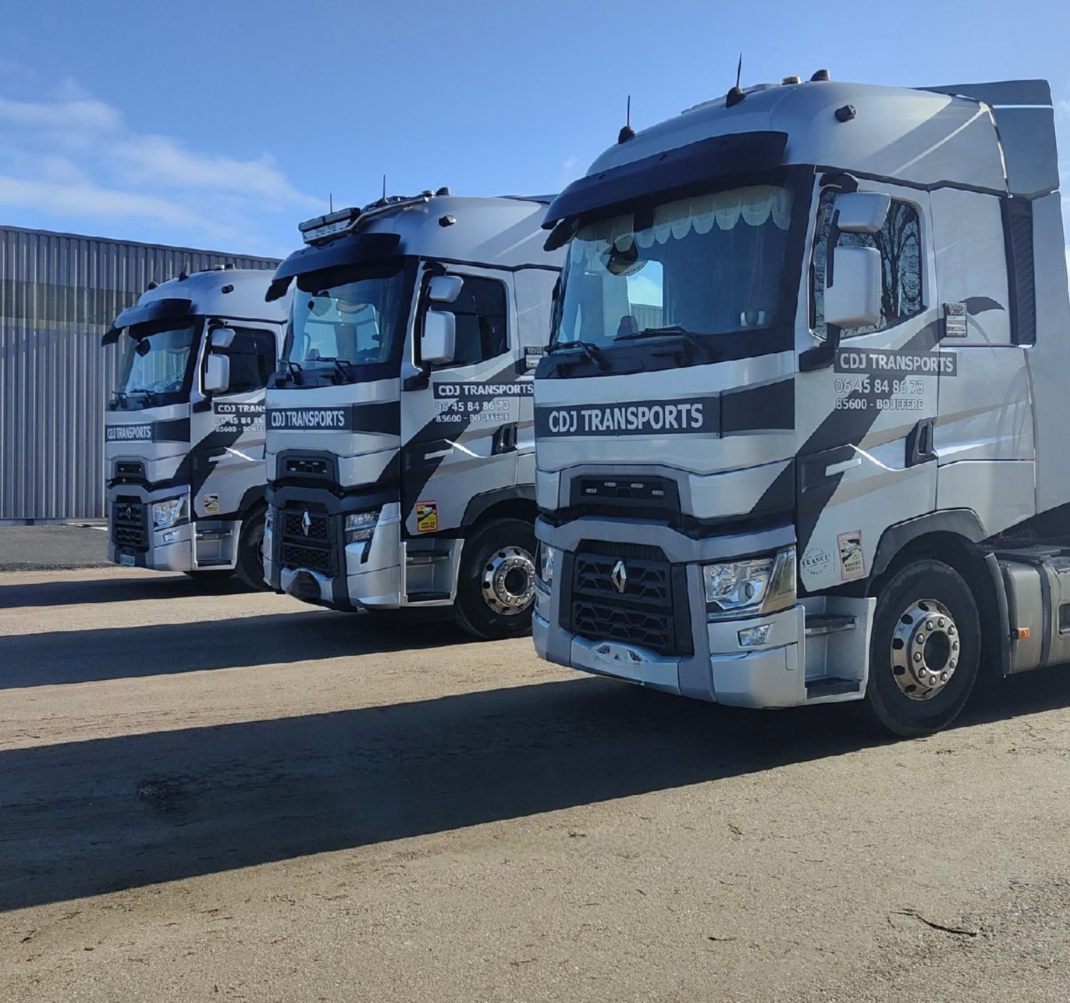 Trois camions de couleur blanche alignés sur une surface de stationnement