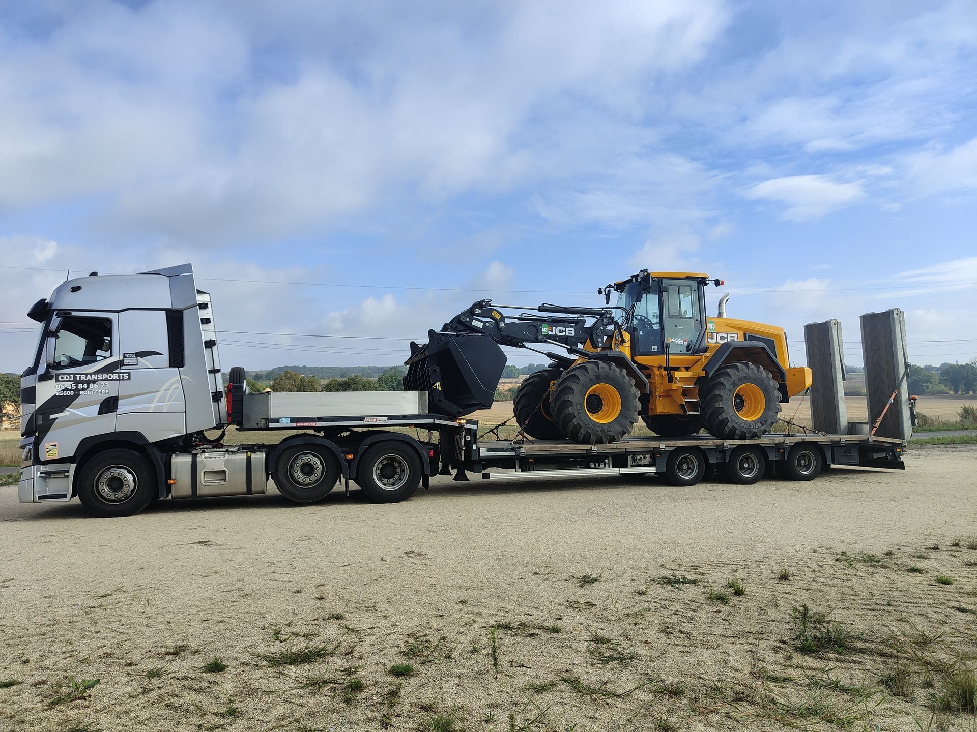 Un camion lourd stationné et transportant un tracteur jaune
