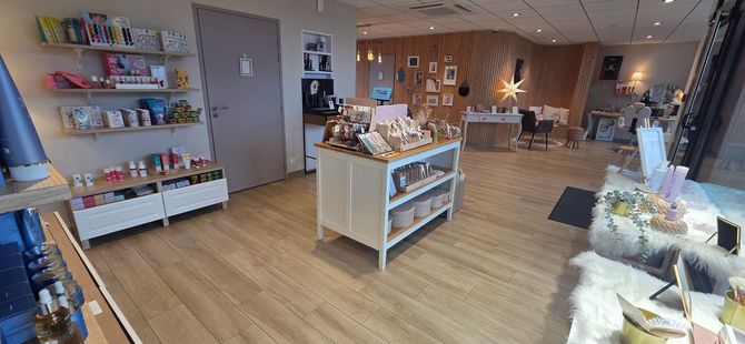 Intérieur lumineux d'une boutique de cadeaux avec des étagères présentant divers articles et une table d'exposition centrale sur un sol en bois.
