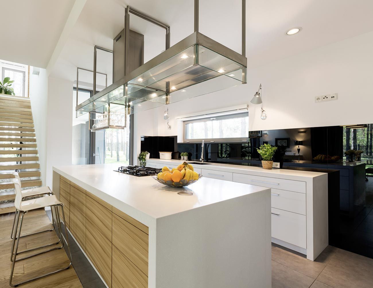 Cocina blanca moderna con isla, gabinetes de madera, campana extractora de acero inoxidable y frutero.