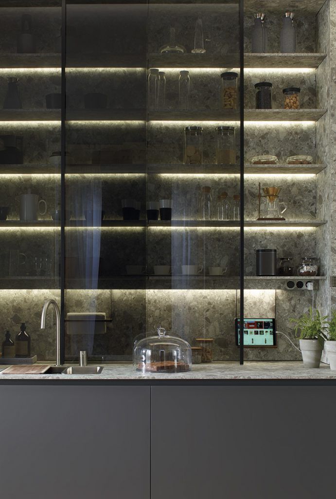 Cocina moderna con gabinetes con frente de vidrio iluminados por luces LED; encimera y gabinetes grises.