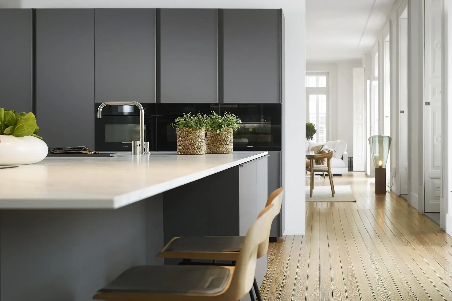 Cocina moderna con gabinetes grises, encimera blanca y pisos de madera clara.