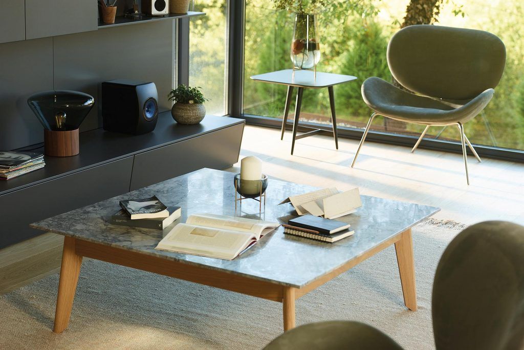 Sala de estar moderna con mesa de café, sillón y altavoz.