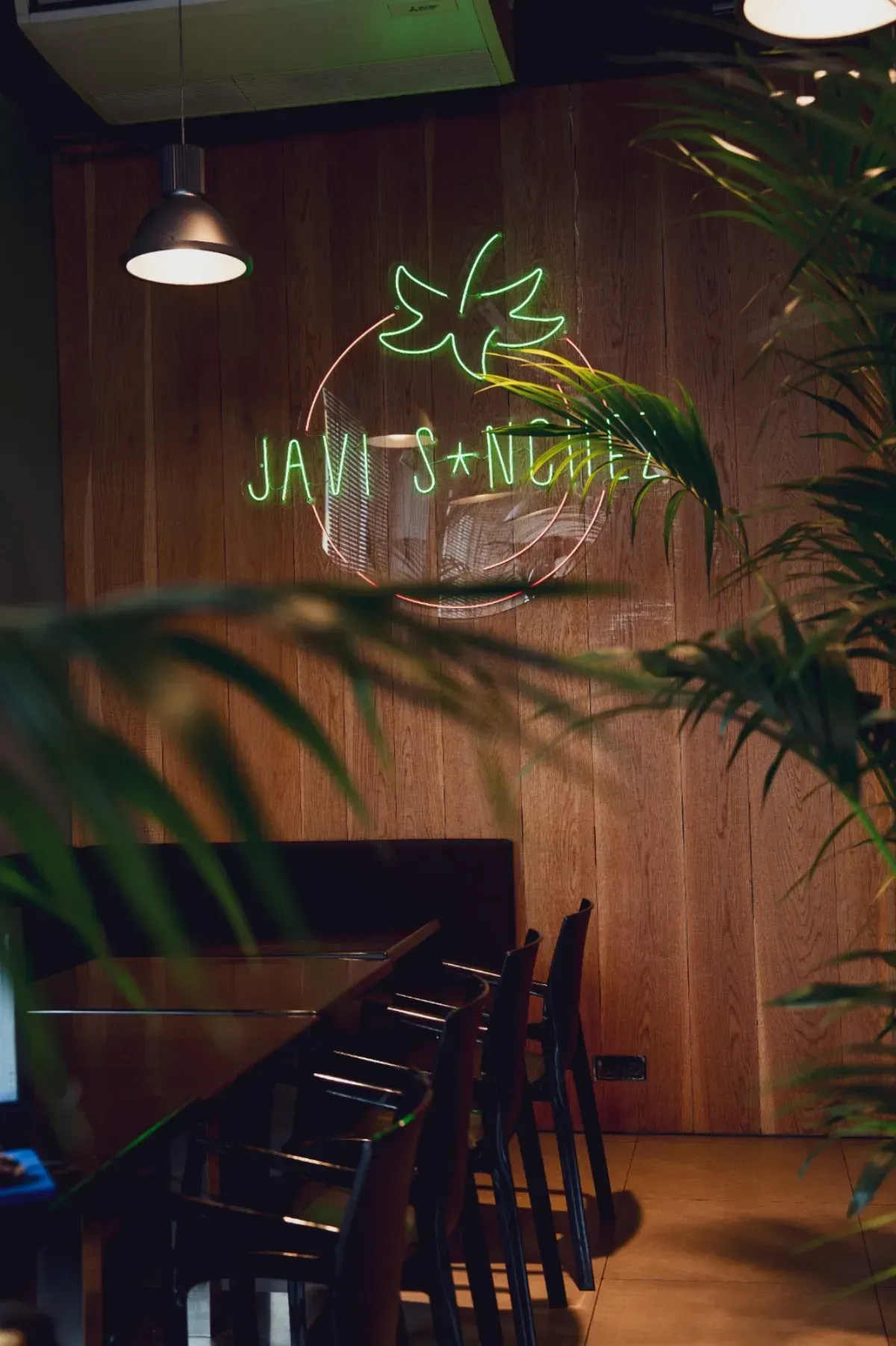 Un letrero de neón verde brillante con la forma de una hoja y las palabras 