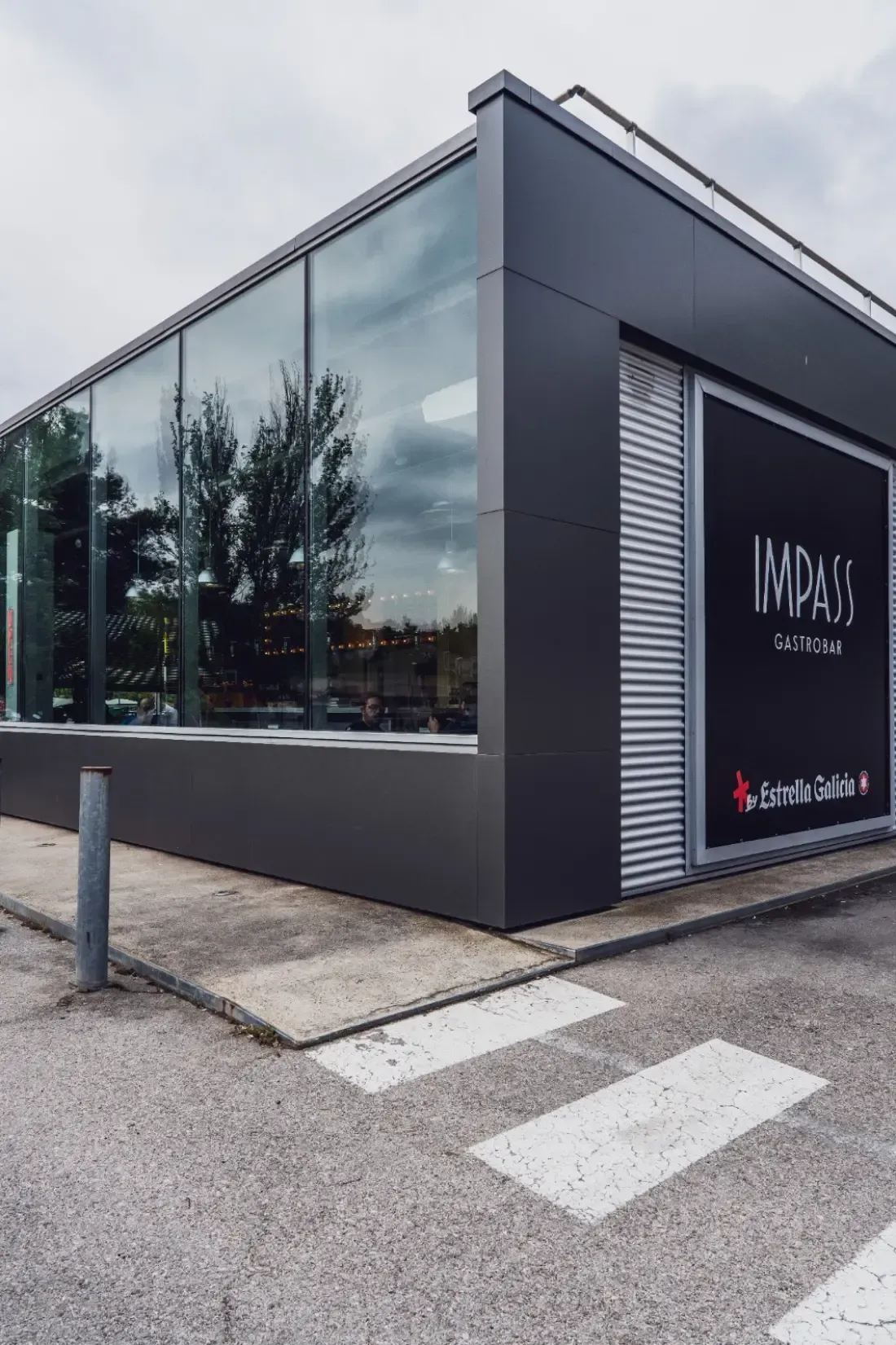 Edificio moderno de fachada gris oscuro con grandes ventanales y un letrero que dice 
