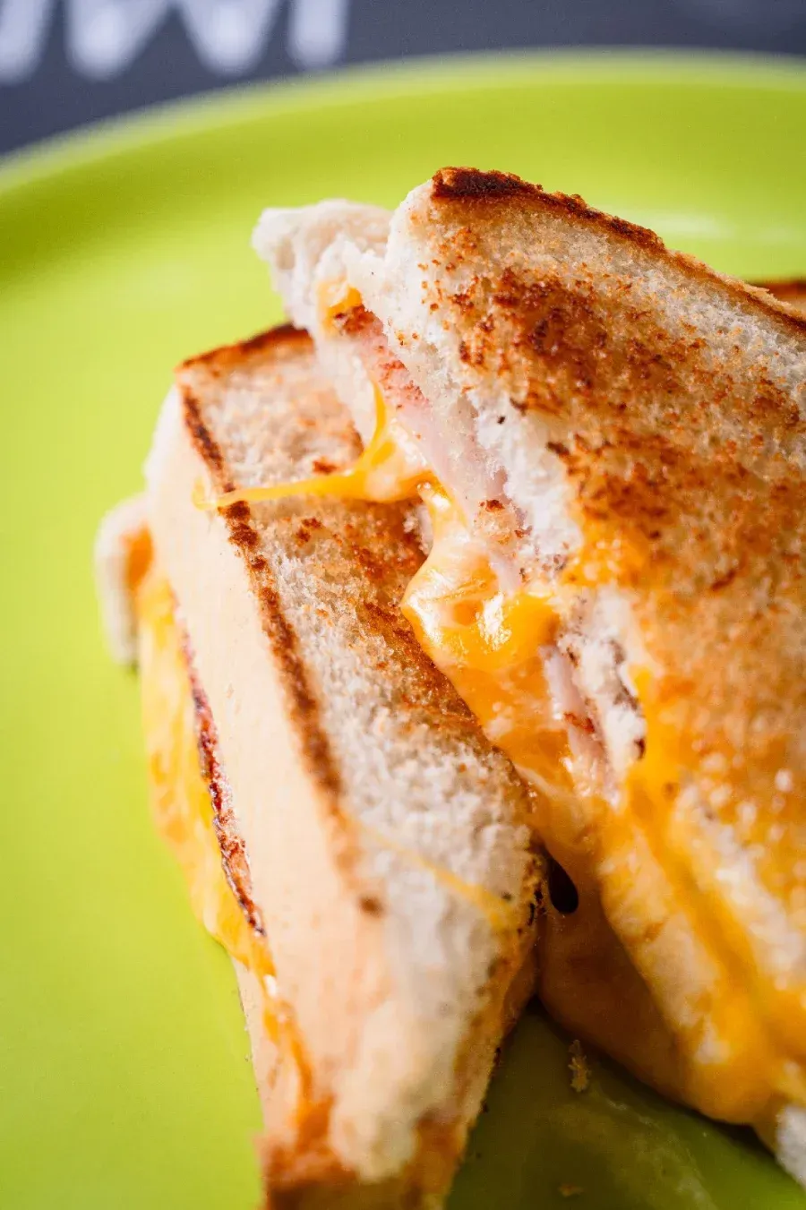 Un sándwich de queso tostado cortado por la mitad, dejando al descubierto el queso amarillo derretido