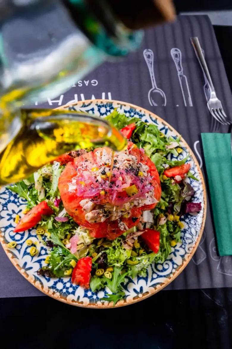 Se vierte aceite de oliva sobre una colorida ensalada con una rodaja grande de tomate