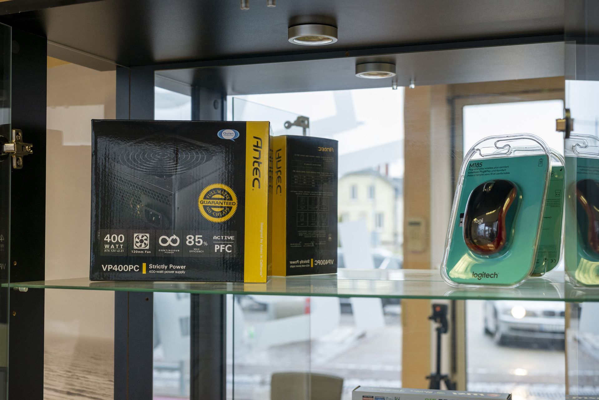 Étagère de présentation avec des appareils électroniques et des accessoires en boîte, près d’une fenêtre