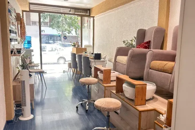 Zona de espera del salón con sillas, mesas pequeñas y una ventana frontal que da a la calle.