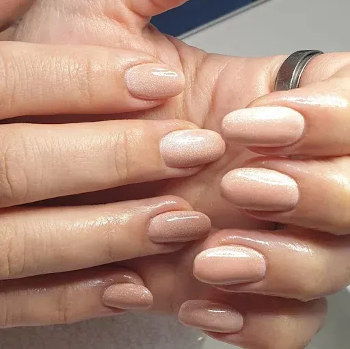 Primer plano de unas manos con uñas pintadas de color rosa pálido y un anillo de plata en un dedo.