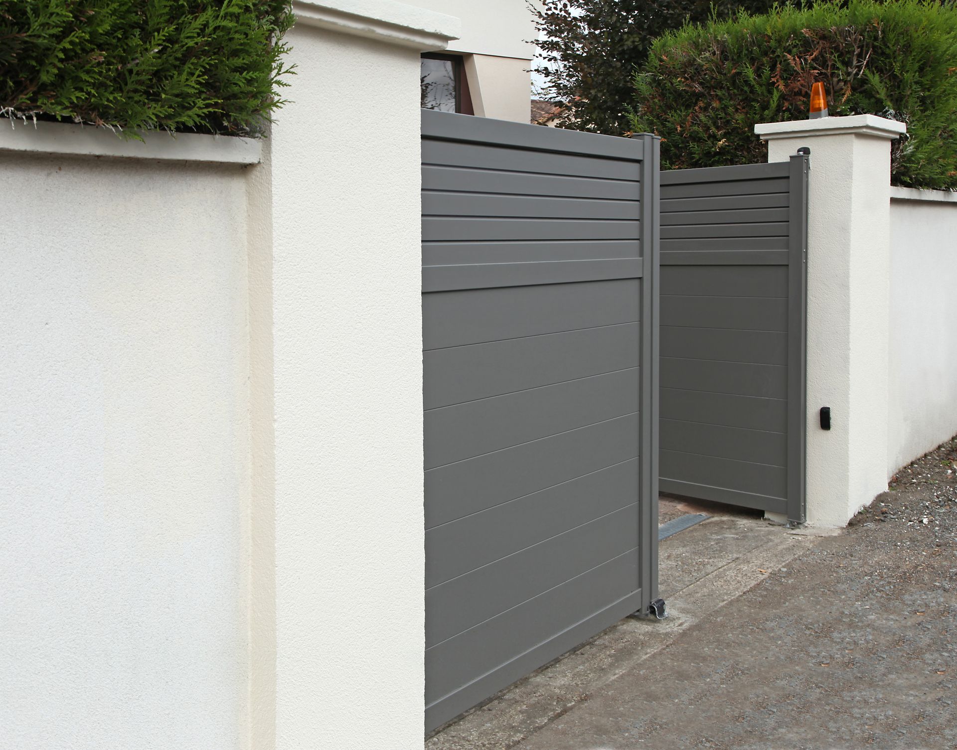 Un portail battant ouvert en aluminium.