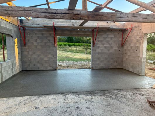 Construction en béton avec murs en parpaings et poutres de toit apparentes.
