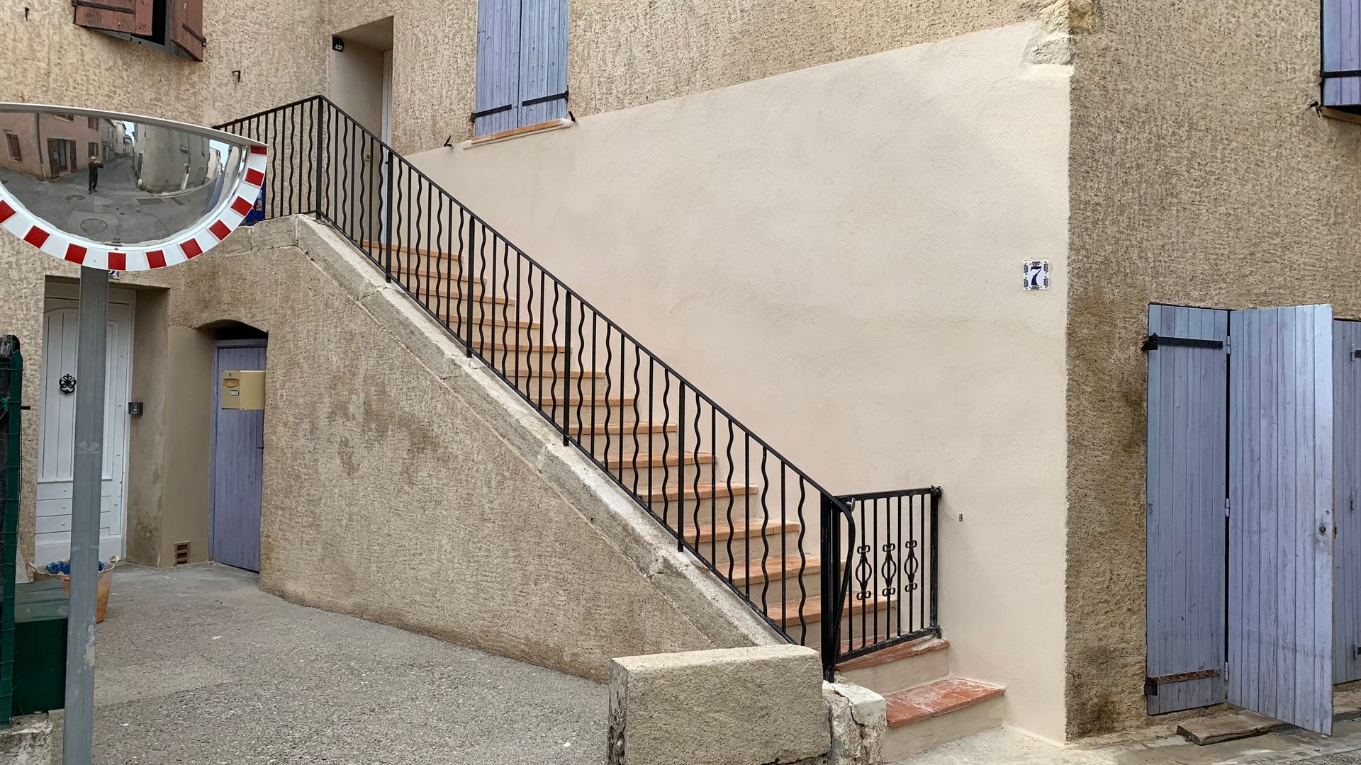 Un escalier extérieur avec un garde-corps et un portillon à l'entrée.