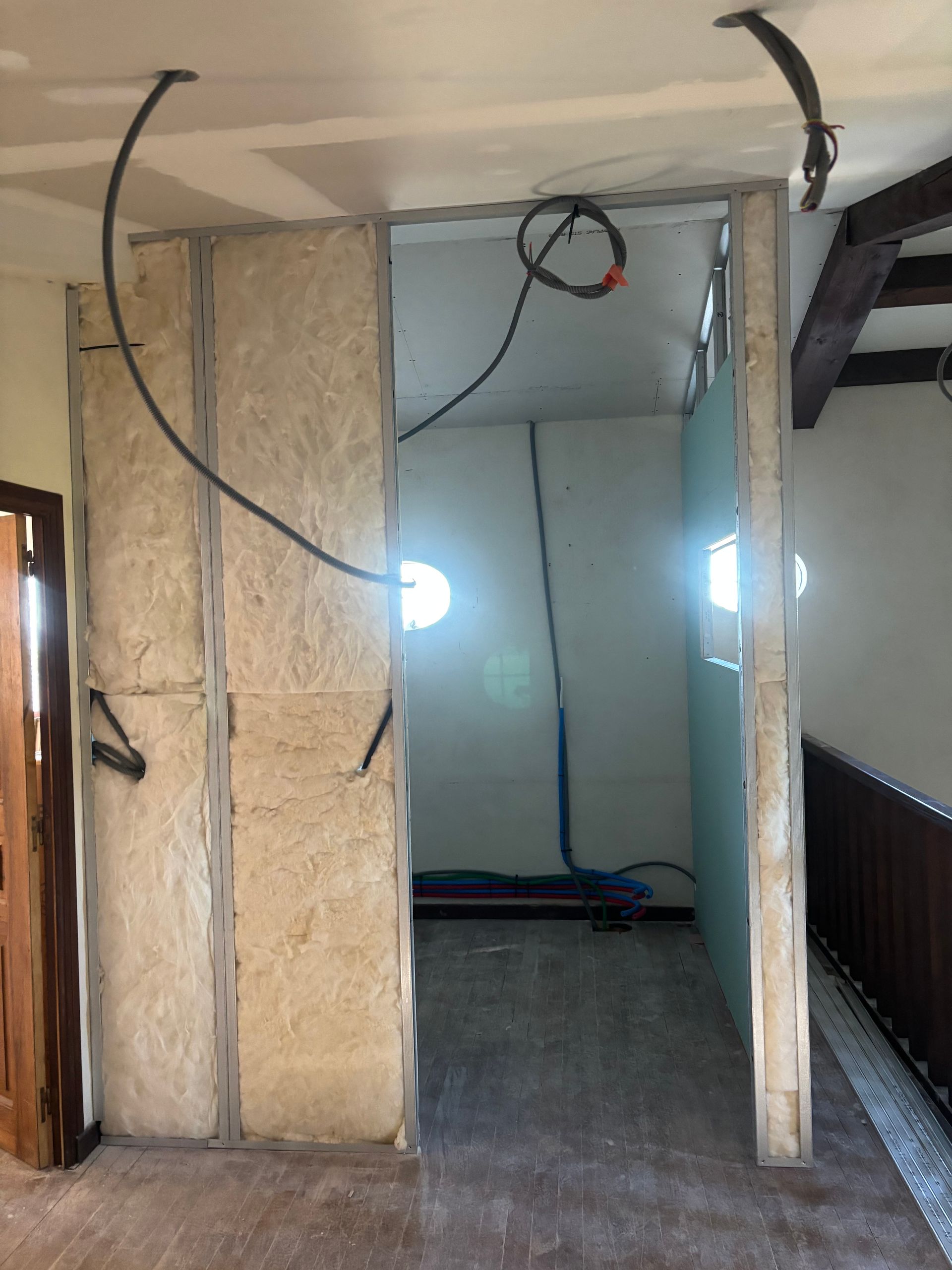 Chantier de rénovation avec câblage apparent, pose de cloisons sèches avec plaques de plâtre et isolant.