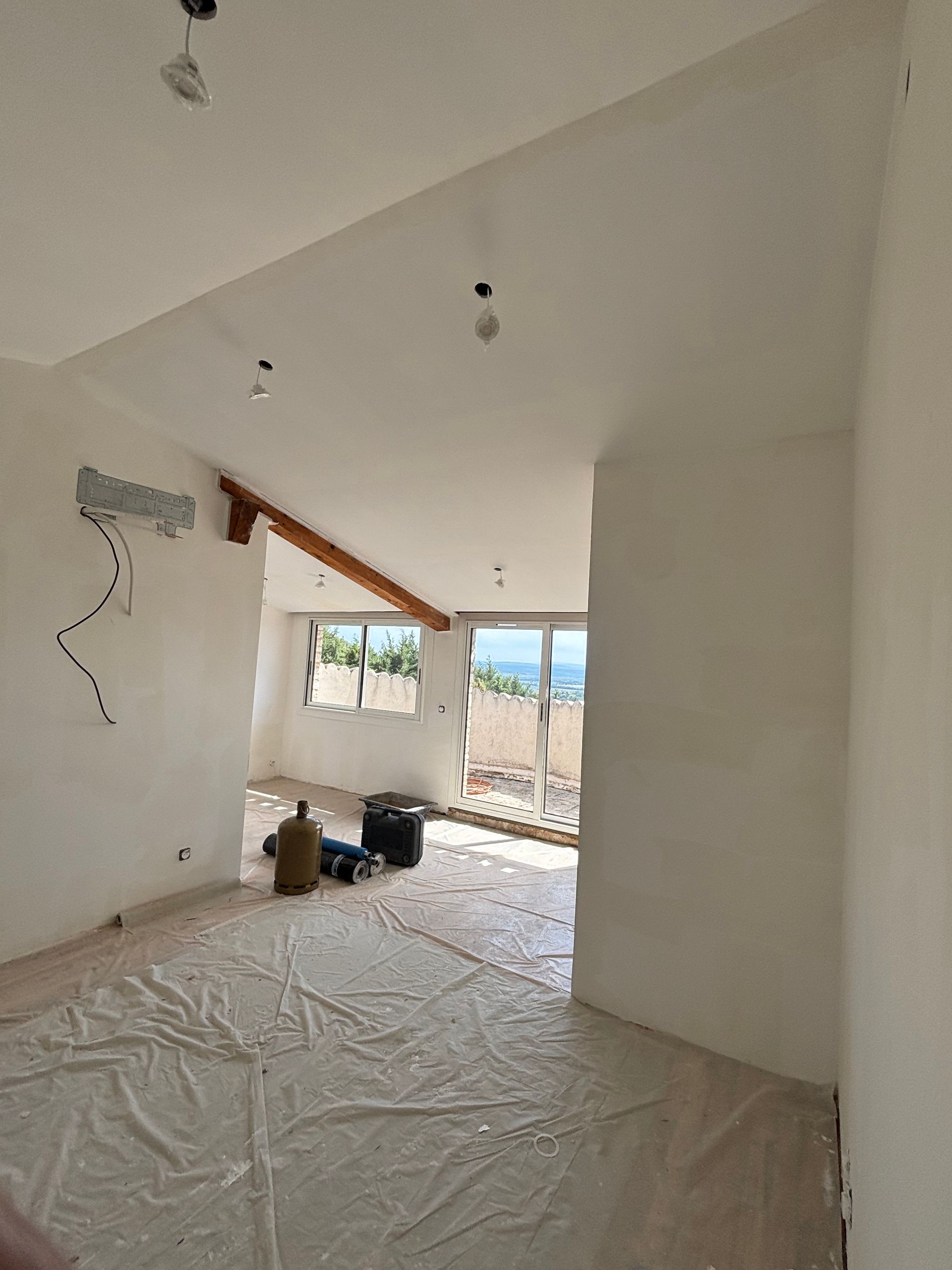 Pièce vide en cours de rénovation, avec le sol recouvert de plastique.