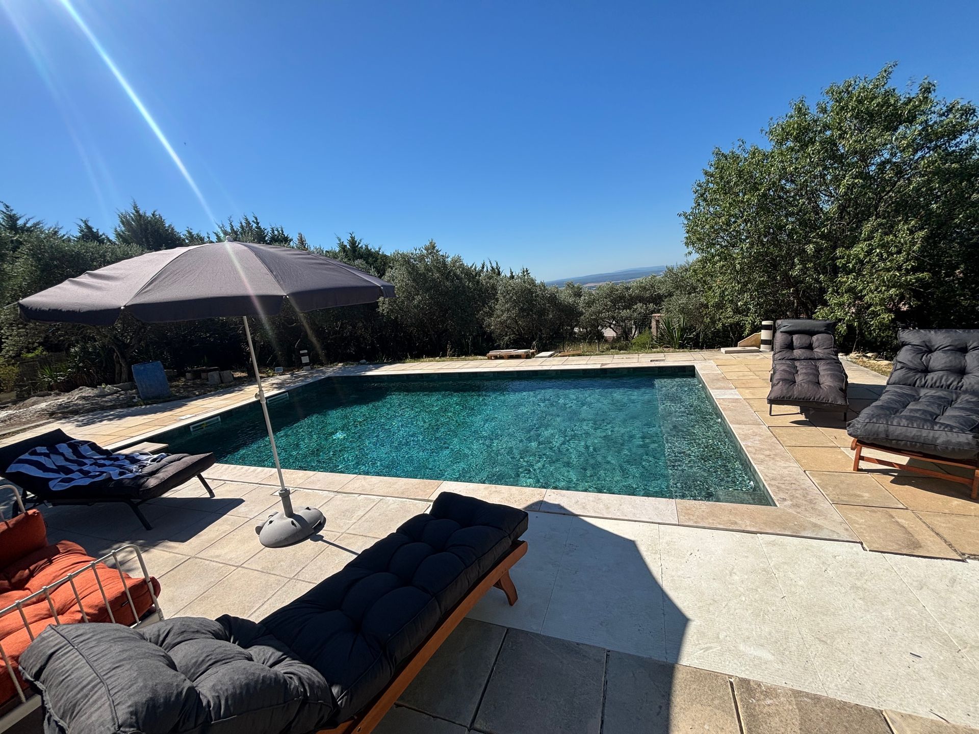Une piscine avec des transats autour et un parasol.