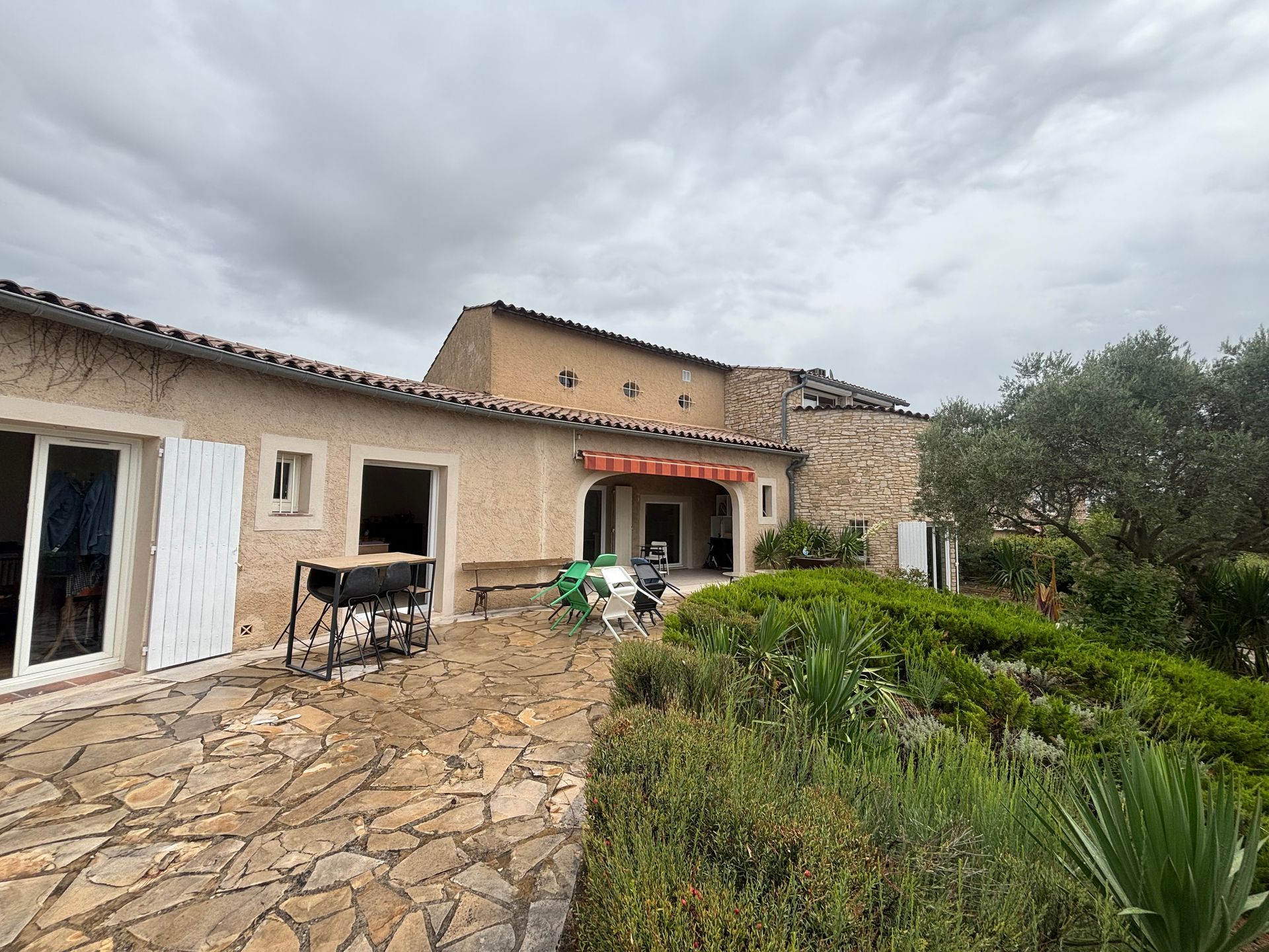Une maison avec une terrasse et des arbustes.