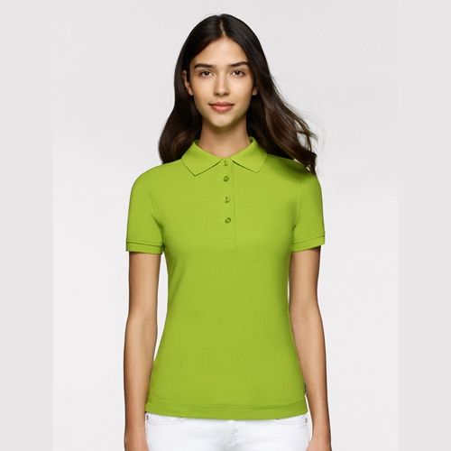 Frau in einem limettengrünen Poloshirt, vor neutralem Hintergrund stehend.