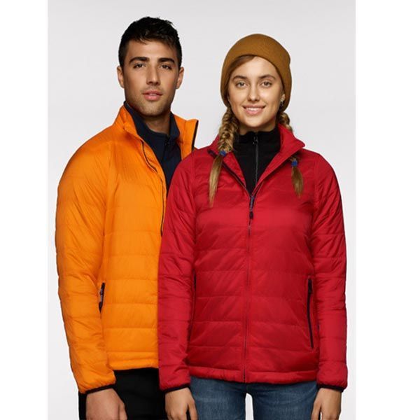 Mann und Frau in orangefarbenen und roten Pufferjacken stehen nebeneinander im Innenbereich.