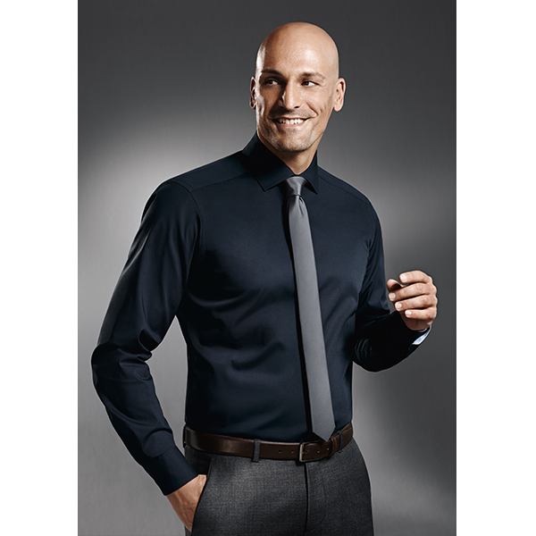 Mann in dunkelblauem Hemd und grauer Krawatte, lächelnd, graue Hose, brauner Gürtel.