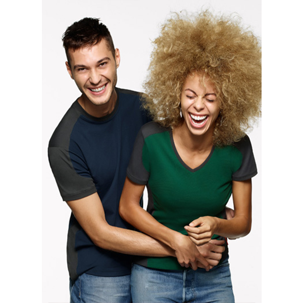 Mann umarmt Frau von hinten, beide lachen; tragen T-Shirts mit Farbblockdesign.