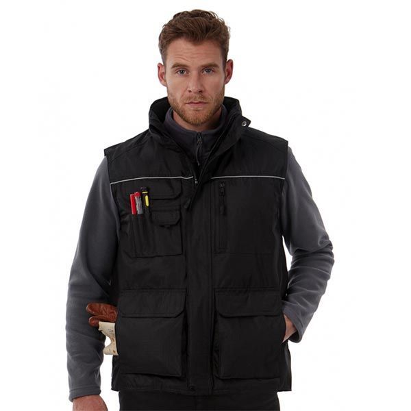 Mann trägt eine schwarze Arbeitsweste mit mehreren Taschen und darunter ein graues Fleece.